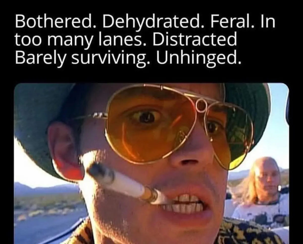 A close-up shot of a man wearing large orange-tinted aviator sunglasses and a green hat, with a cigarette in his mouth…
