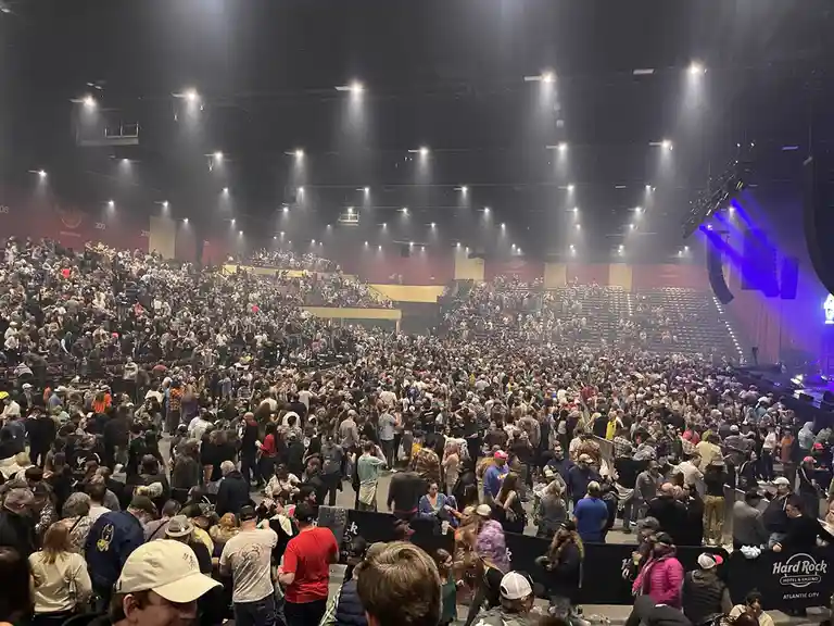 A crowded indoor concert venue, likely the Hard Rock Hotel & Casino in Atlantic City, is packed with people milling about in…