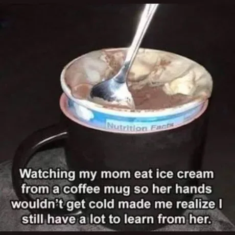 A close-up photo shows a coffee mug with a spoon stuck in a container of chocolate ice cream, which is sitting inside the…