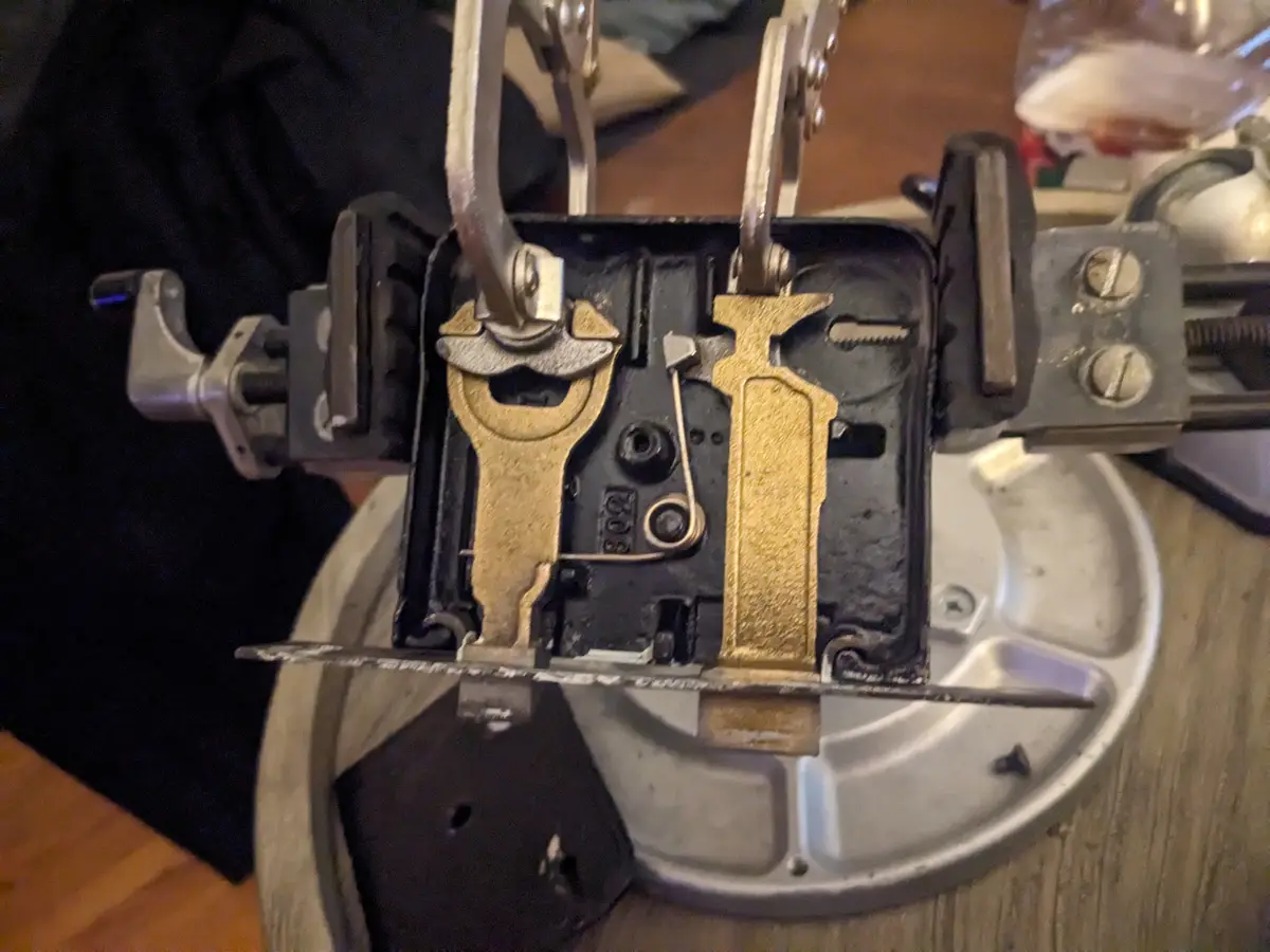 A close-up photo shows the internal mechanism of an old mechanical typewriter, with its brass typebars and levers visible…