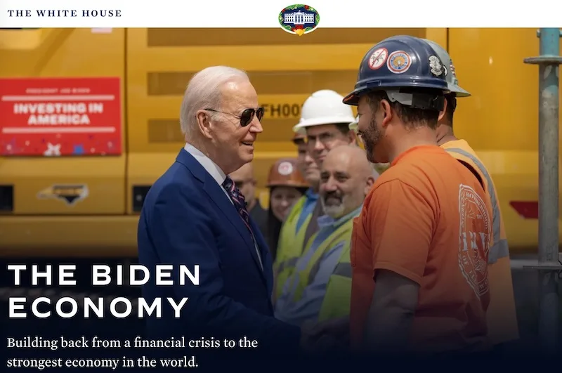 A photo shows President Joe Biden shaking hands with a construction worker wearing a hard hat and orange shirt, surrounded…