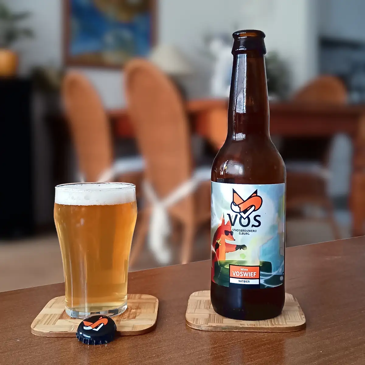 A brown beer bottle with a label featuring a cartoon fox wearing sunglasses and the text 'VOS STADSBRUWERIJ ELBURG Witte…