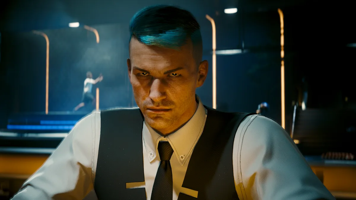 A close-up of a man with blue-tinted hair, wearing a white shirt, black vest, and tie, staring intensely at the viewer…