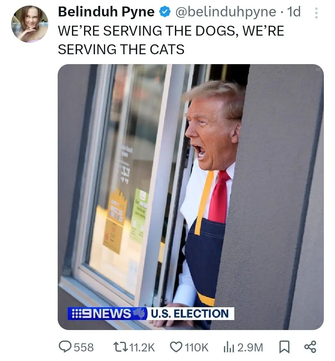 A man in a fast-food worker's uniform with a red tie and blue apron peers out from behind a drive-thru window, mouth open in…