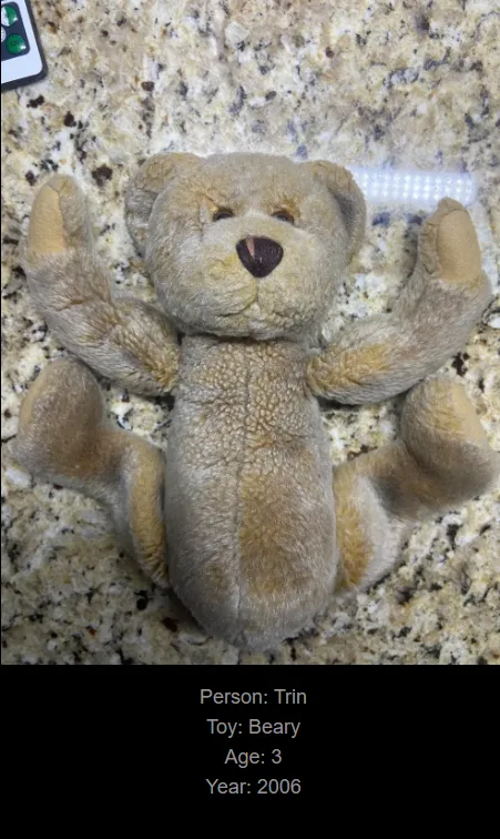 A light brown plush teddy bear lies flat on its back on a speckled granite countertop, arms and legs spread out. Overlaid…