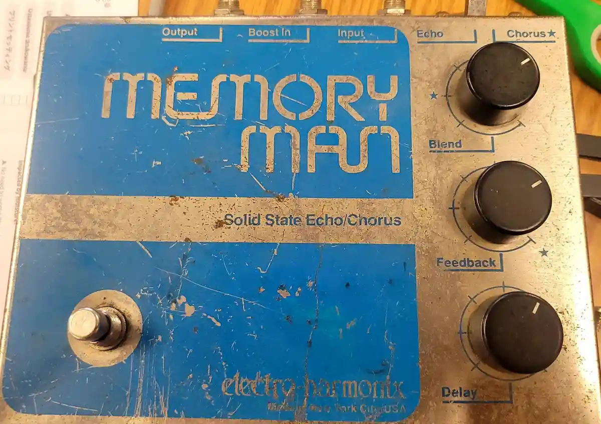 A heavily worn, blue and silver Electro-Harmonix 'Memory Man' guitar effects pedal with three knobs labeled Echo, Blend, and…