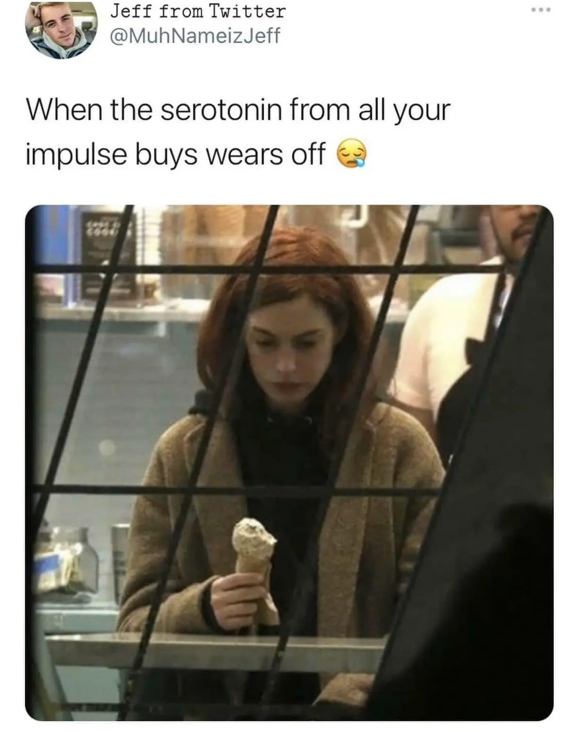 A woman with reddish-brown hair wearing a beige coat and black hoodie is seen holding a partially eaten ice cream cone…