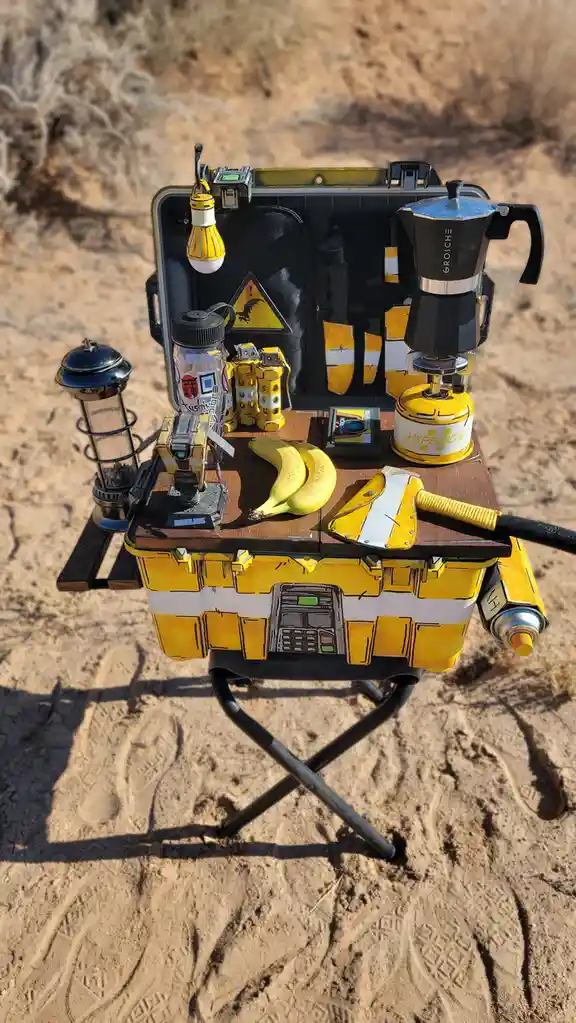 A yellow and black portable camping station, styled to look like a Borderlands game item, is set up in a desert. It holds a…