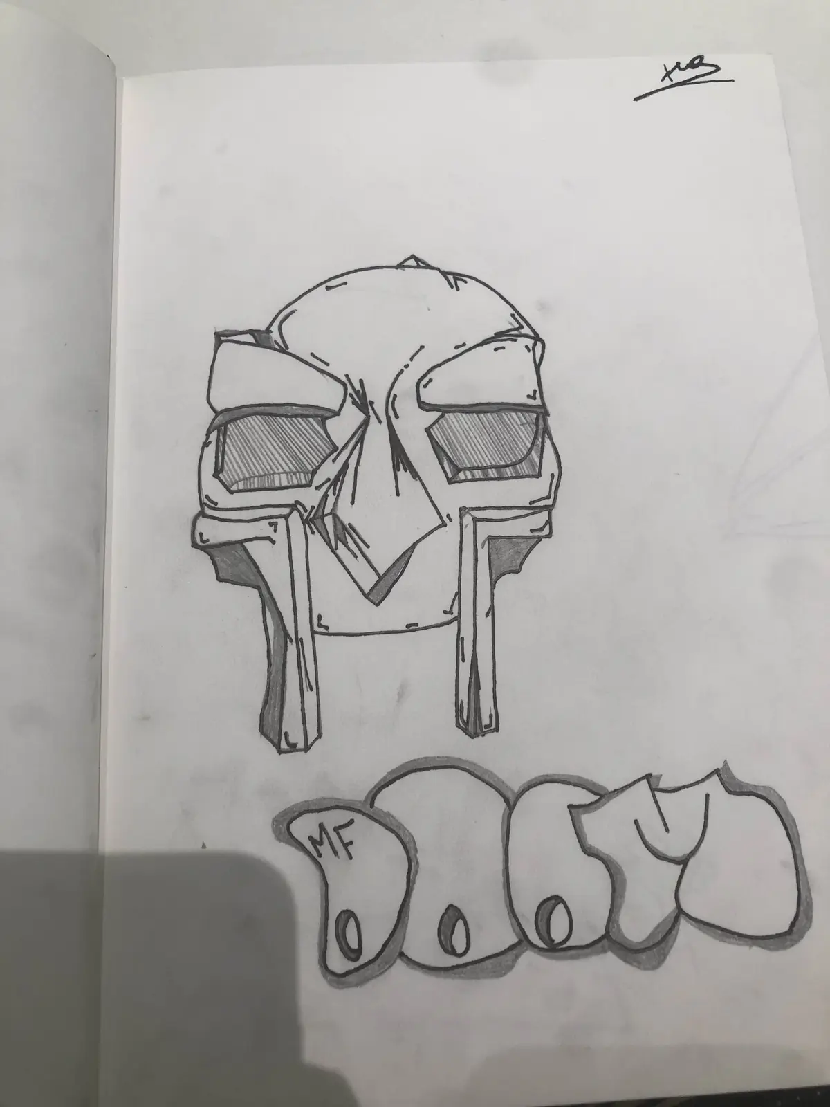 A pencil sketch on paper shows a stylized, angular skull with a broken nose and shaded eye sockets, positioned above a row…