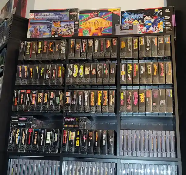 A large, organized shelf filled with numerous Super Nintendo Entertainment System game cartridges and box art, including…