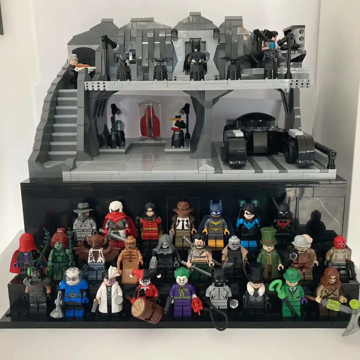 A detailed Lego Batman Batcave diorama with Batman minifigures on the upper level and a large group of Lego Batman villains…