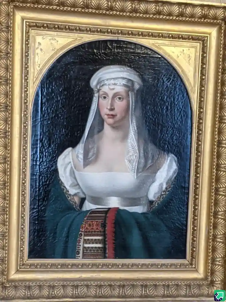 A portrait of a woman in a white headdress and dress with a dark blue background, framed in ornate gold, overlaid with the…