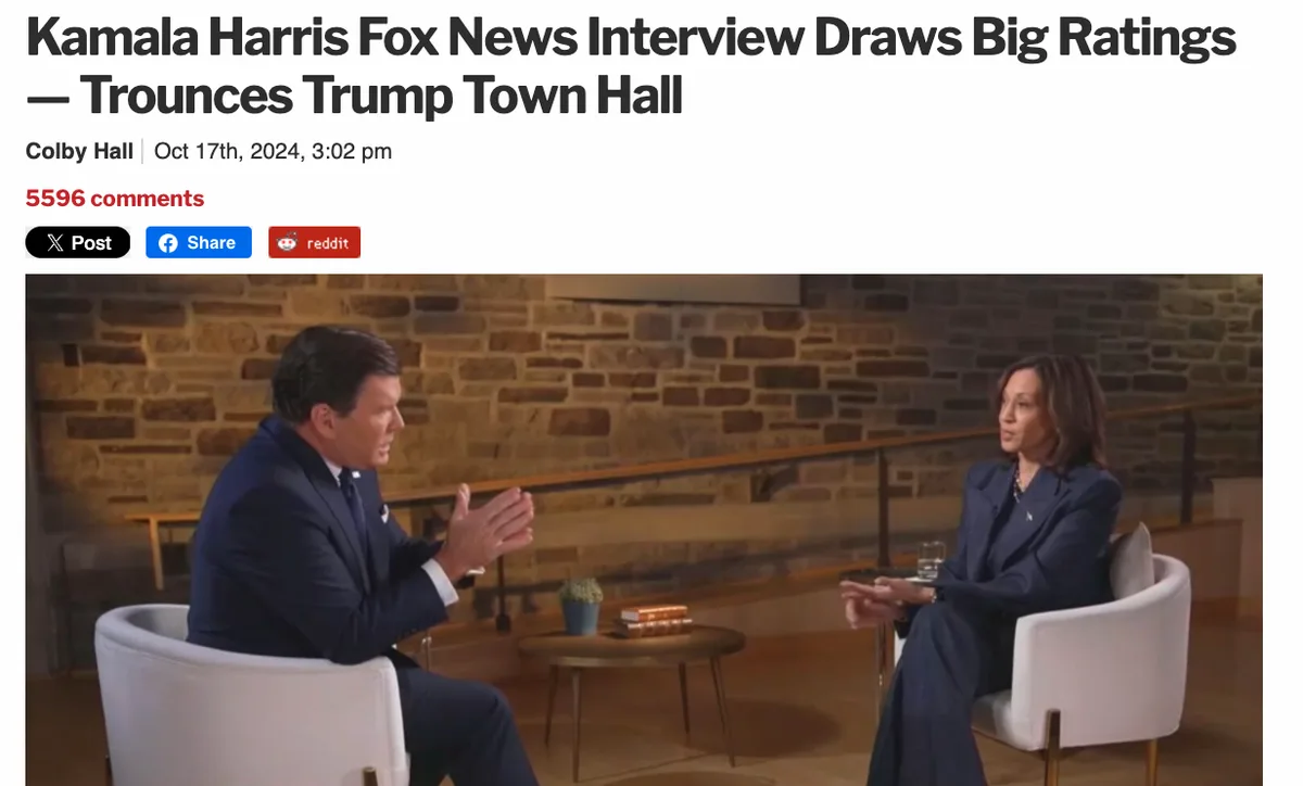 A screenshot of a news article header showing Kamala Harris and a male interviewer seated in white chairs against a brick…