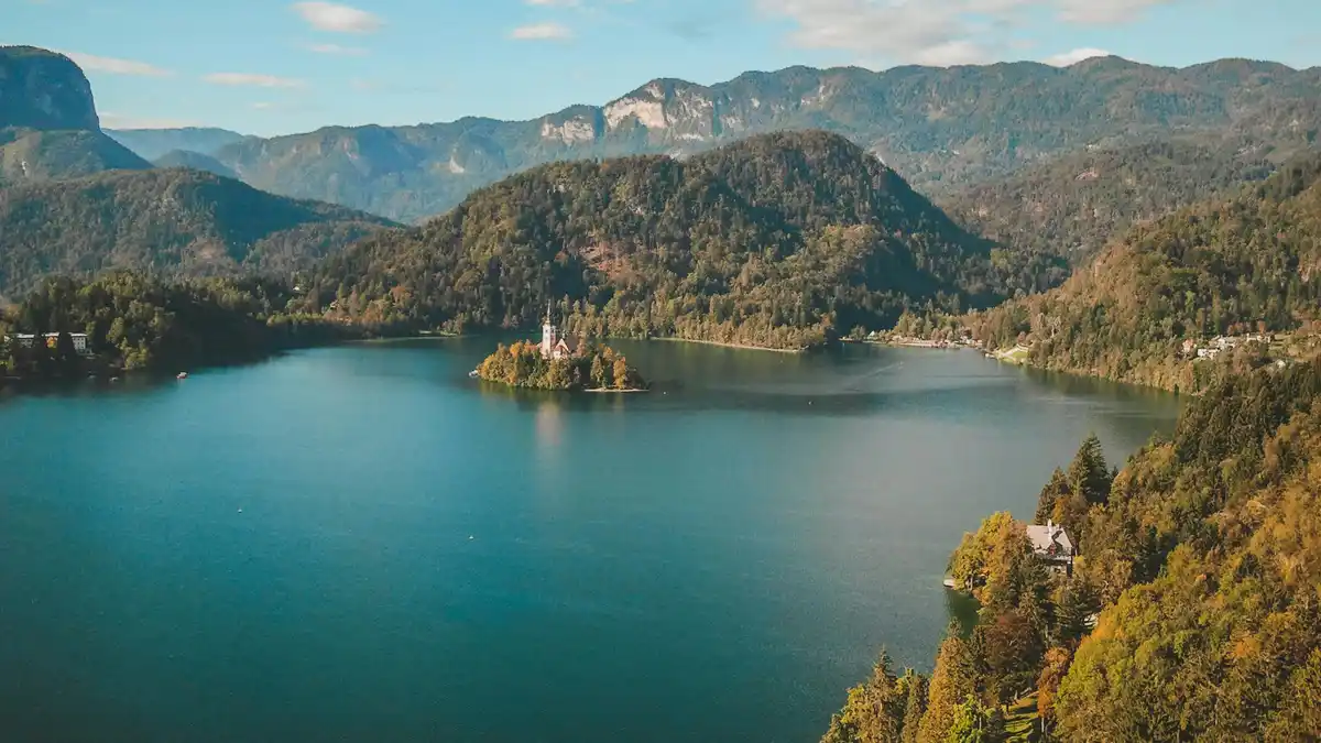 A majestic lake unfolds, its tranquil surface reflecting the surrounding mountains' rugged grandeur. The iconic island…