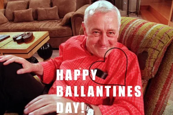 An older man with white hair sits smiling in a red plaid shirt on a striped couch, with a coffee table and brown sofa in the…