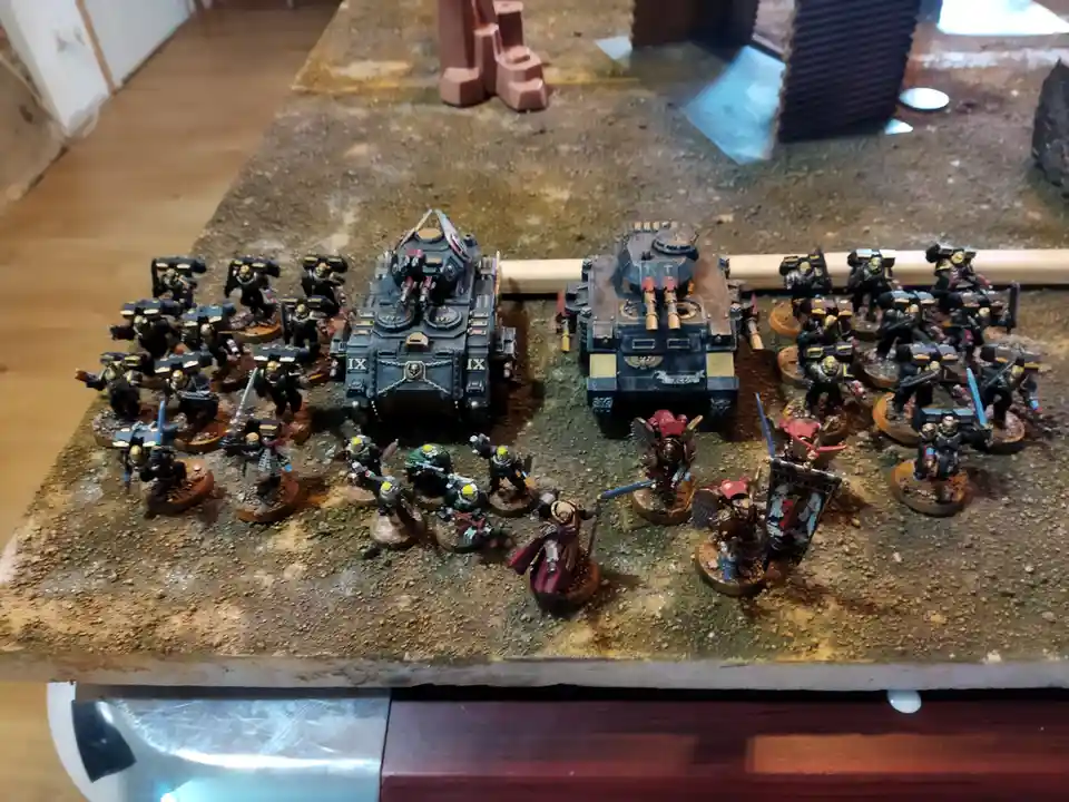 A photo of a large collection of painted miniature warhammer 40k models arranged on a textured gaming table, featuring two…