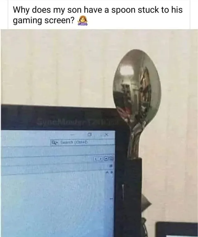 A large metal spoon is visibly stuck to the top right corner of a computer monitor displaying a search interface. The…