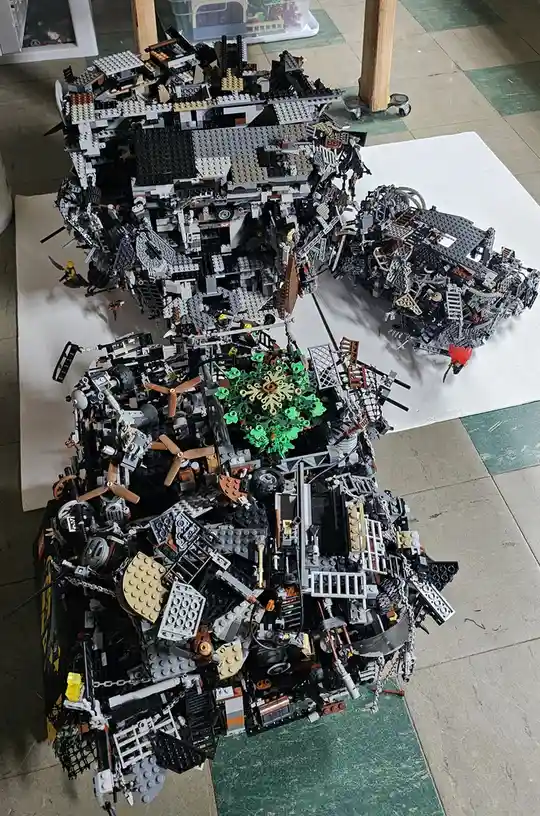 An overhead photo shows a massive, intricate, and chaotic Lego model of a ship, constructed from thousands of black, gray…