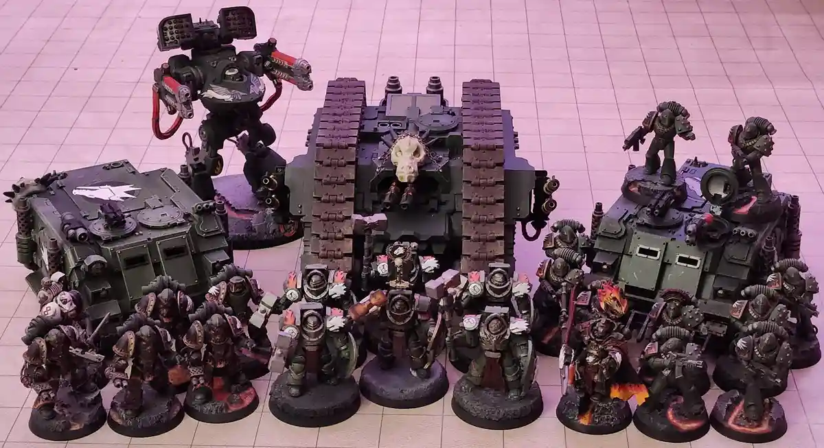 A collection of intricately painted Warhammer 40,000 miniatures, including heavily armored infantry, a large tank with a…