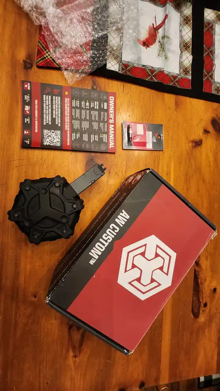 An overhead shot shows a red and black box labeled 'AW CUSTOM™' with a white hexagonal logo, next to a black, star-shaped…