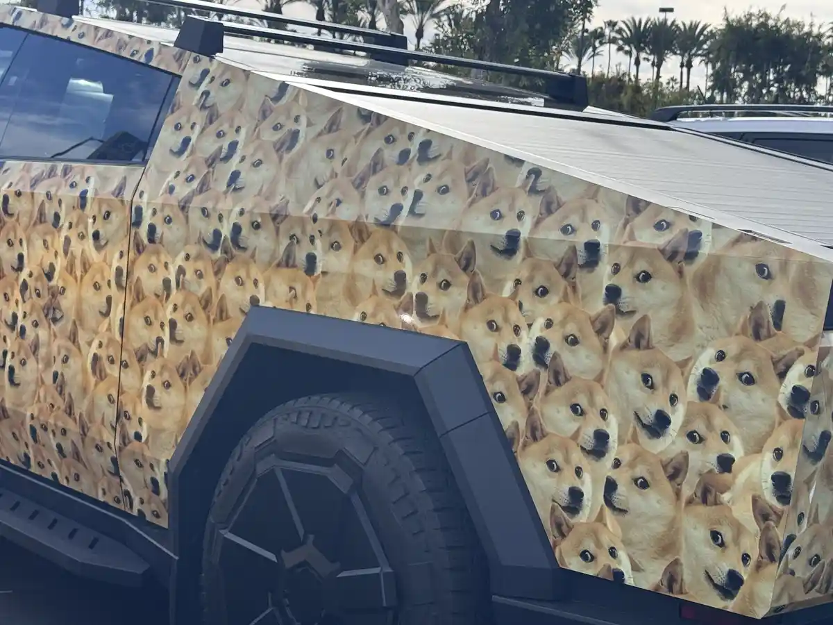 A vehicle, likely a truck or SUV, is covered in a repeating pattern of the 'Doge' meme image featuring a Shiba Inu dog with…