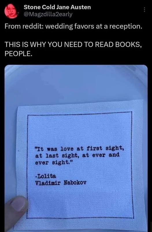 A close-up photo shows a hand holding a small, light blue cloth napkin with black text stitched onto it. The text reads: 'It…
