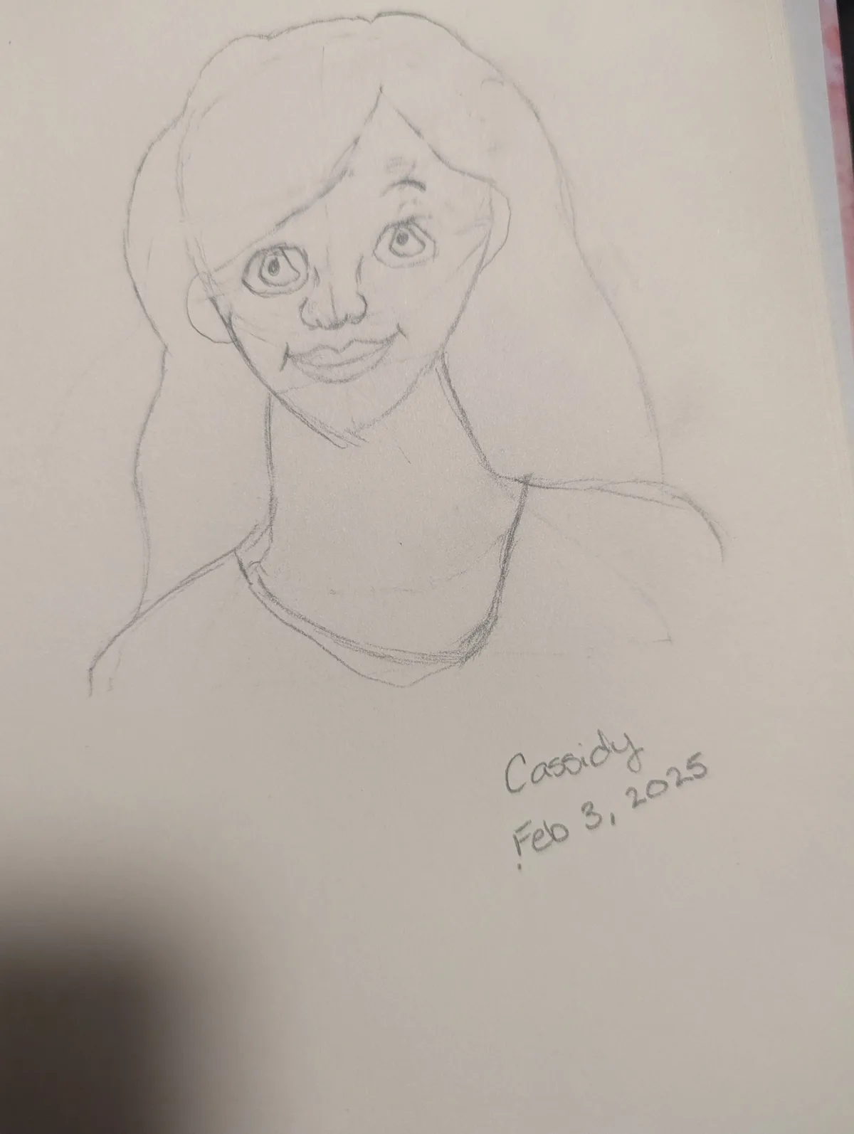 A pencil sketch of a person's head and shoulders, showing a stylized face with large eyes and a smile, drawn on white paper…