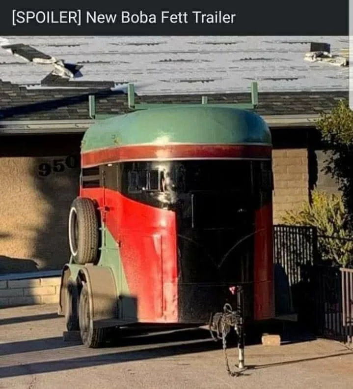 A large, custom-built trailer parked in a driveway, painted with the iconic red and green color scheme of Boba Fett's armor…