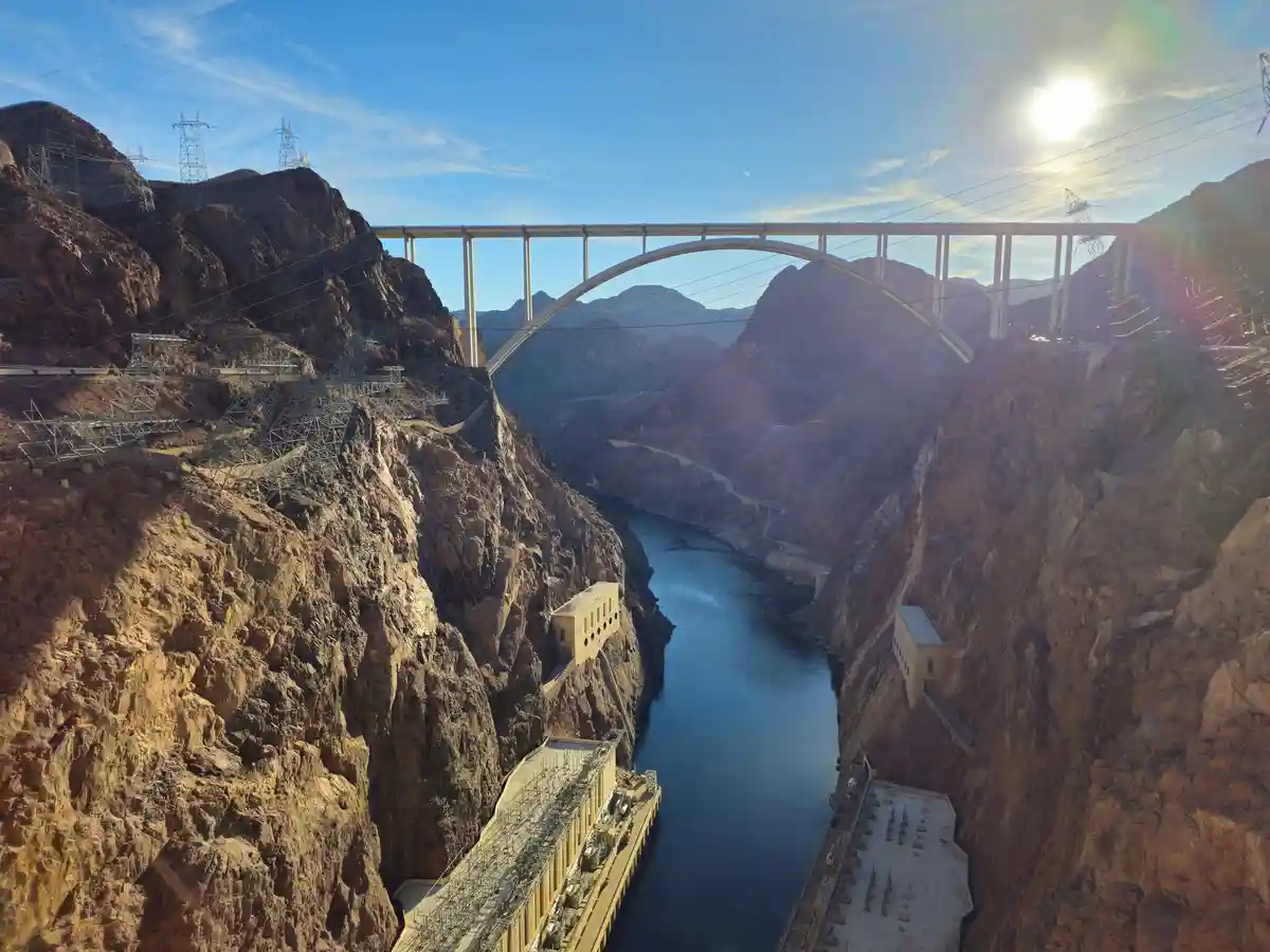 A wide-angle photo of the Hoover Dam and the Mike O'Callaghan–Pat Tillman Memorial Bridge spanning a deep canyon with a…