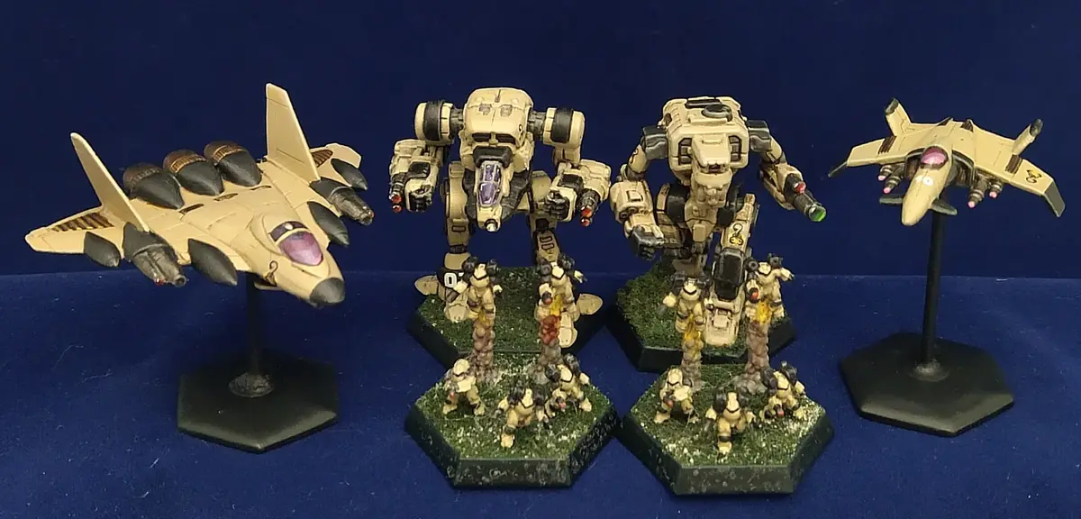 Four painted miniature models — two fighter jets and two giant mechs with small soldier figures at their bases — are…