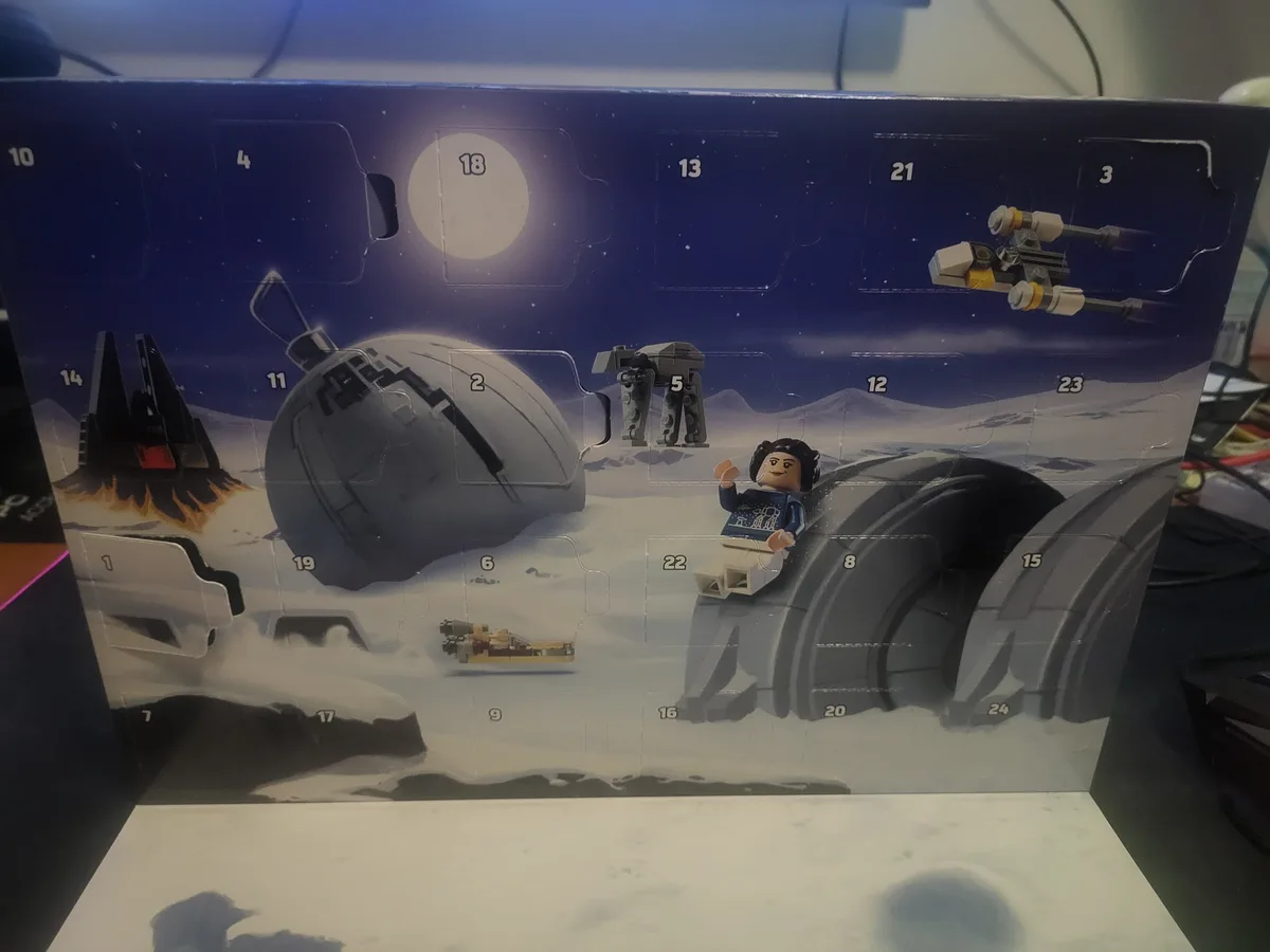 A close-up photo of a LEGO Star Wars Advent Calendar box, showing a snowy Hoth scene with numbered flaps. Visible are a LEGO…
