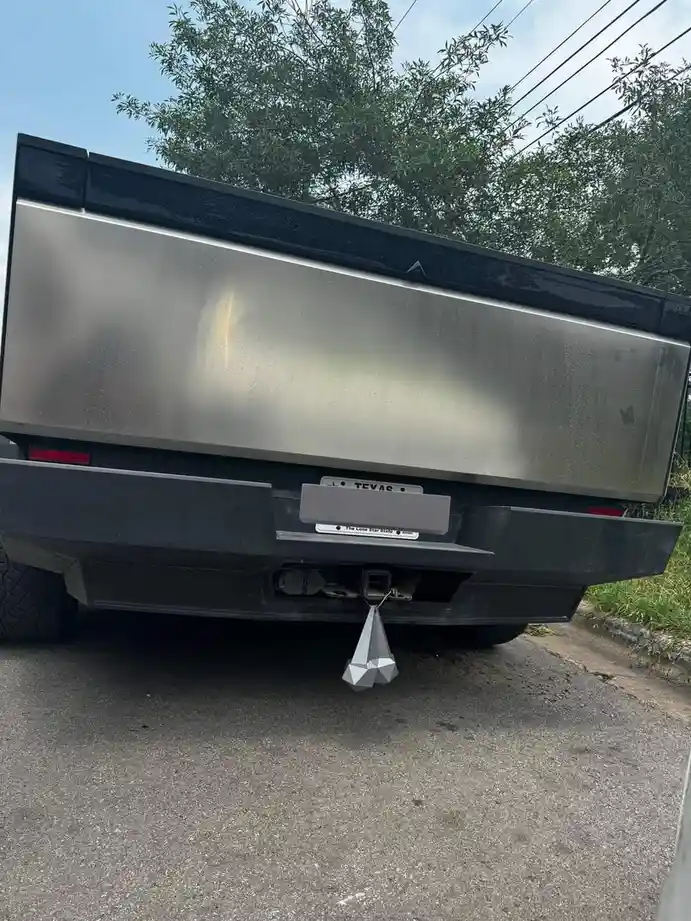 The rear view of a black pickup truck with a stainless steel bed, a Texas license plate, and a geometric, faceted silver…