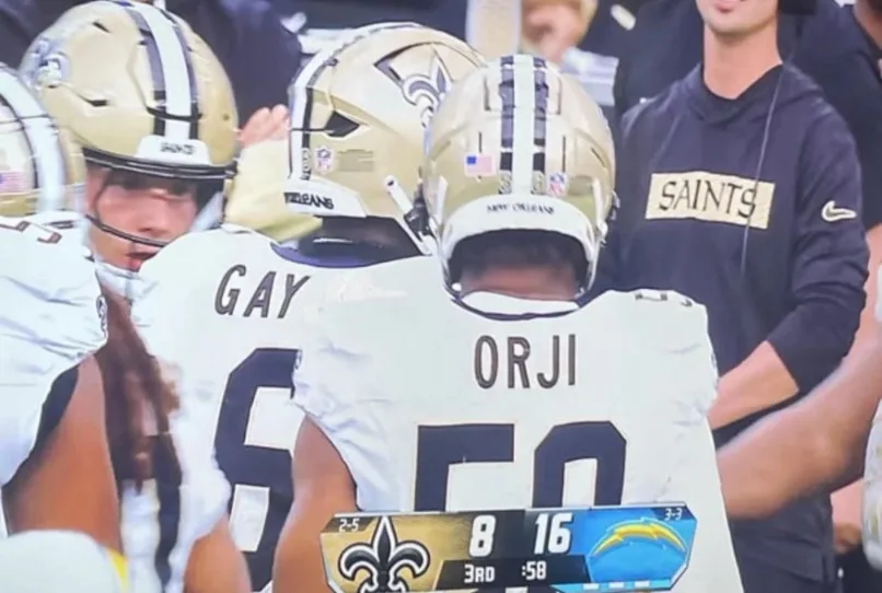 A close-up shot of New Orleans Saints football players huddled together on the field, with the back of player #50, ORJI…