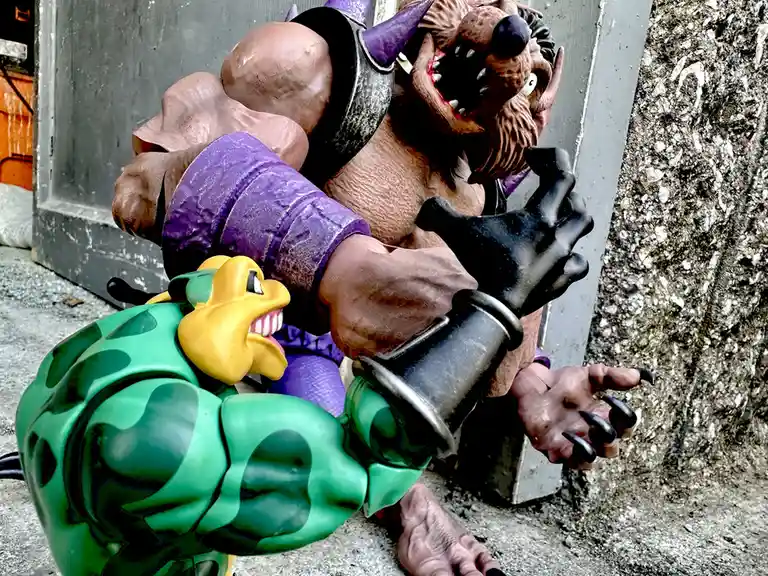 A large, muscular, brown-skinned monster figure with a wolf-like head, purple armor, and black gloves is pinning down a…