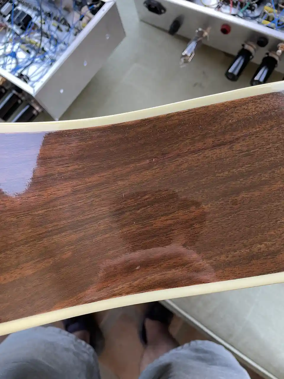 A close-up photo shows a glossy, dark brown wooden surface with a visible crack running horizontally across it, framed by a…