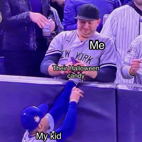 A man in a New York baseball jersey labeled 'Me' leans over a barrier, smiling as he hands a piece of candy to a young child…