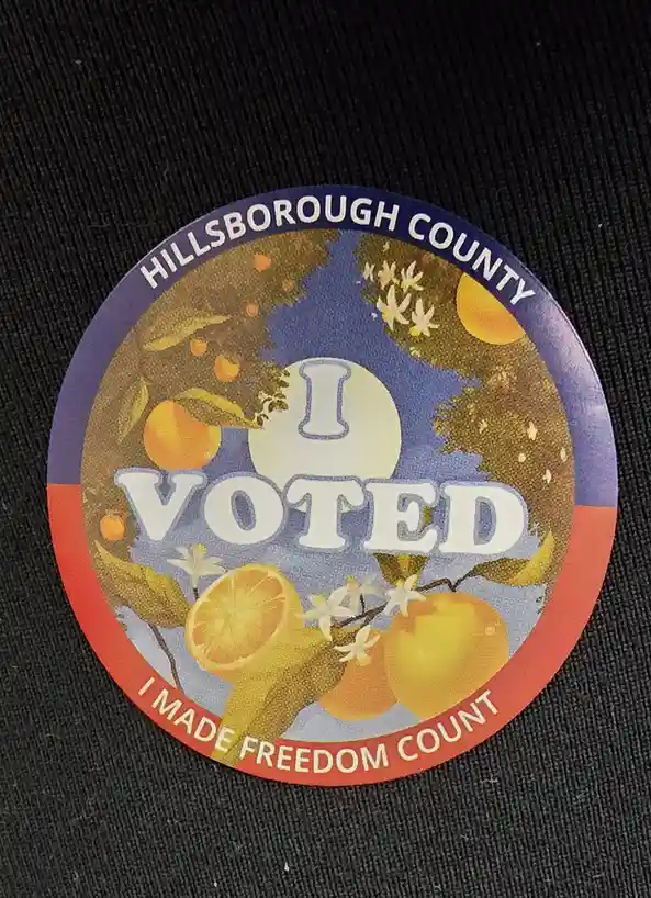 A circular Hillsborough County 'I VOTED' sticker with orange-themed artwork, including whole and sliced oranges, orange…