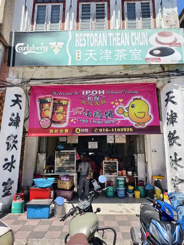 A photo of a bustling street food stall in Ipoh, Malaysia, named 'Restoran Thean Chun' with Chinese characters and a…