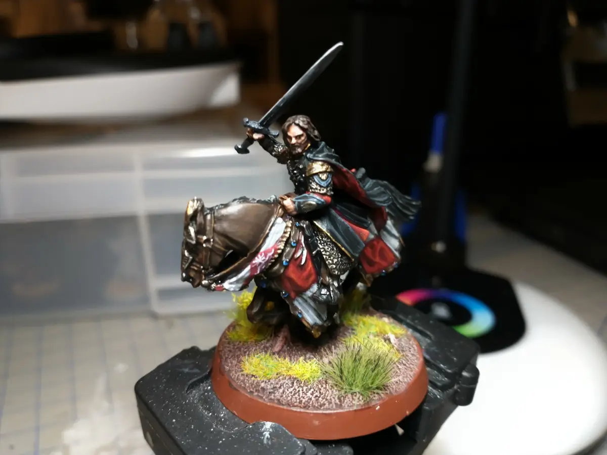 A highly detailed, hand-painted miniature of a bearded knight on horseback, wielding a sword, mounted on a circular base…