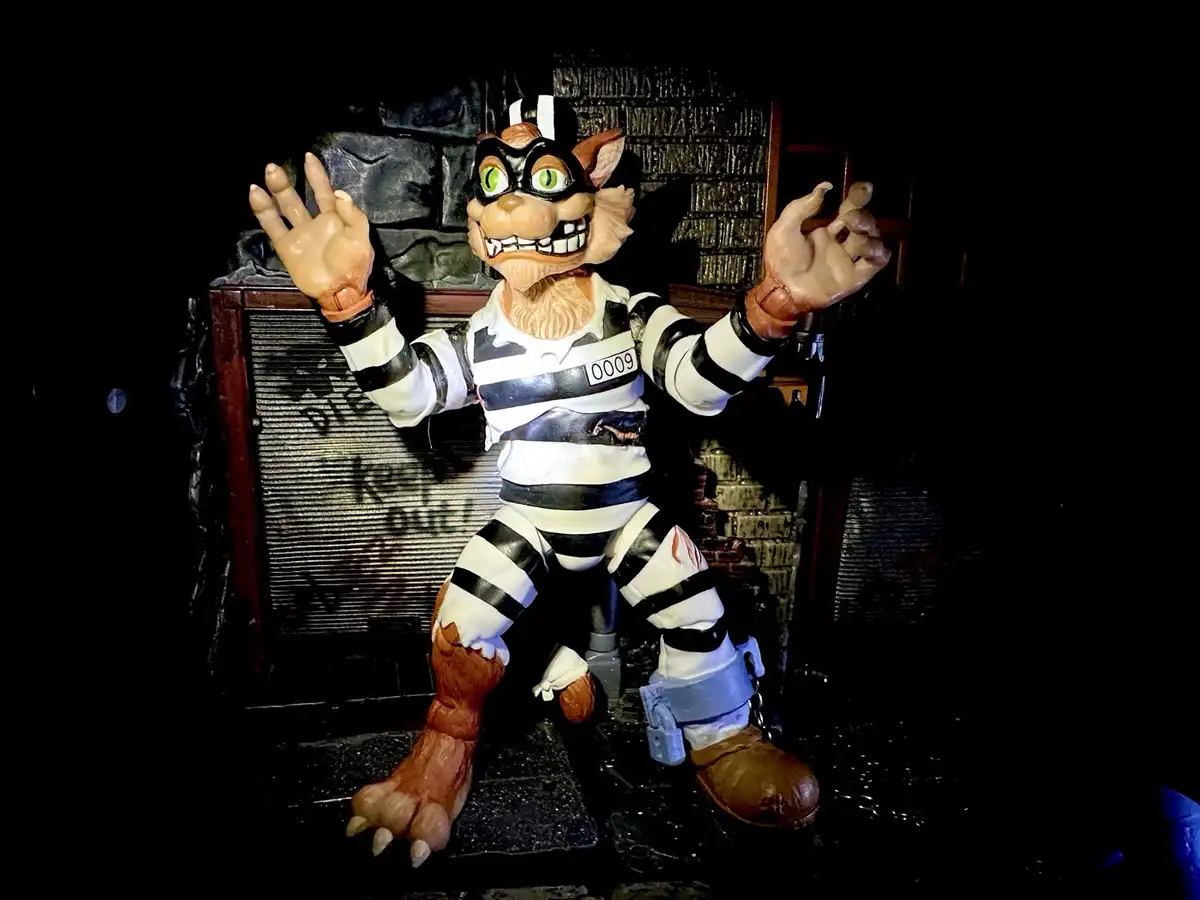 A menacing, anthropomorphic cat statue dressed in a torn black-and-white striped prison uniform with the number 0009 on its…