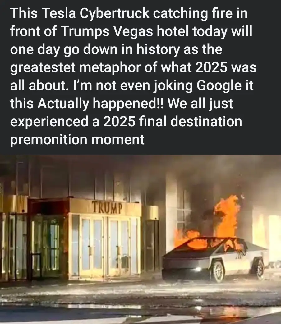 A Tesla Cybertruck is engulfed in flames on a street at night, positioned directly in front of the entrance to a building…