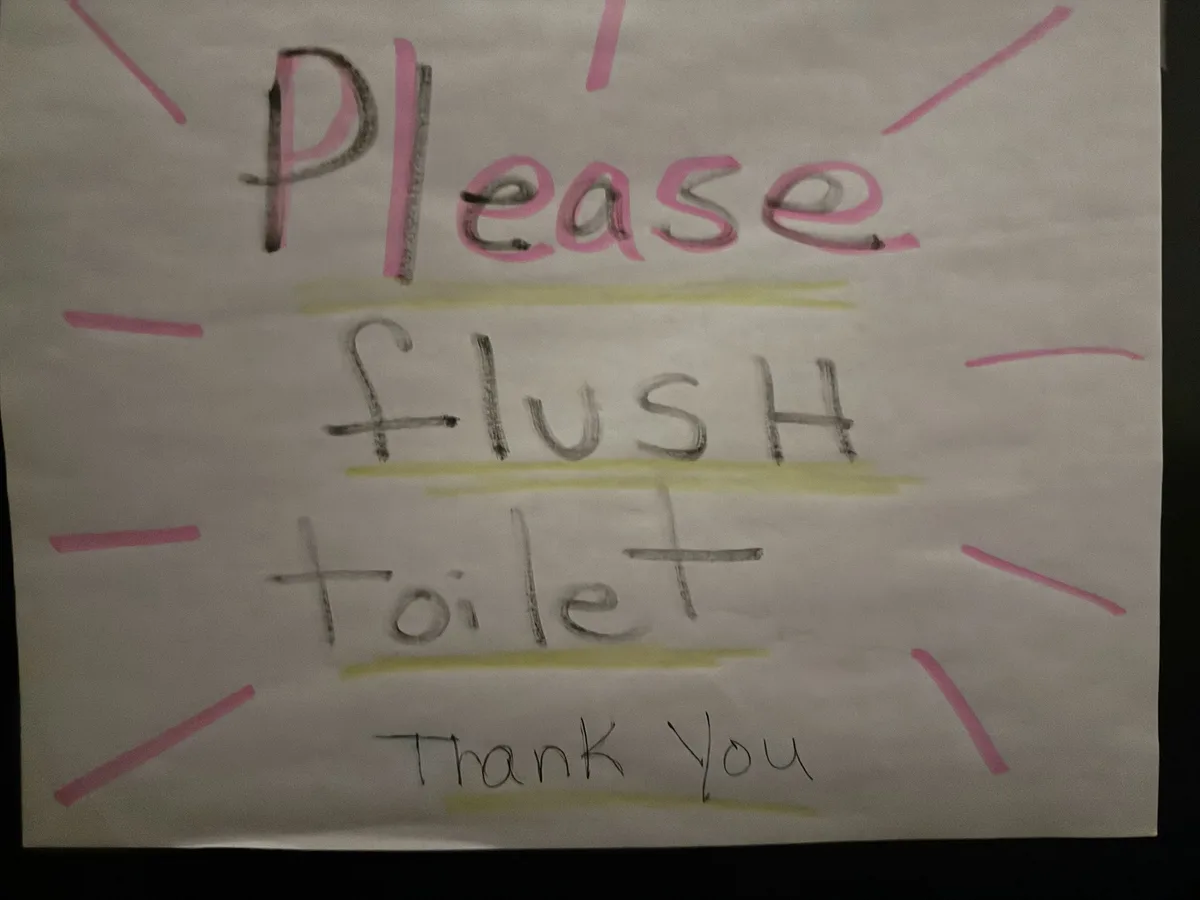 A hand-drawn sign on white paper with the words 'Please flush toilet Thank You' written in black marker, with 'Please' and…