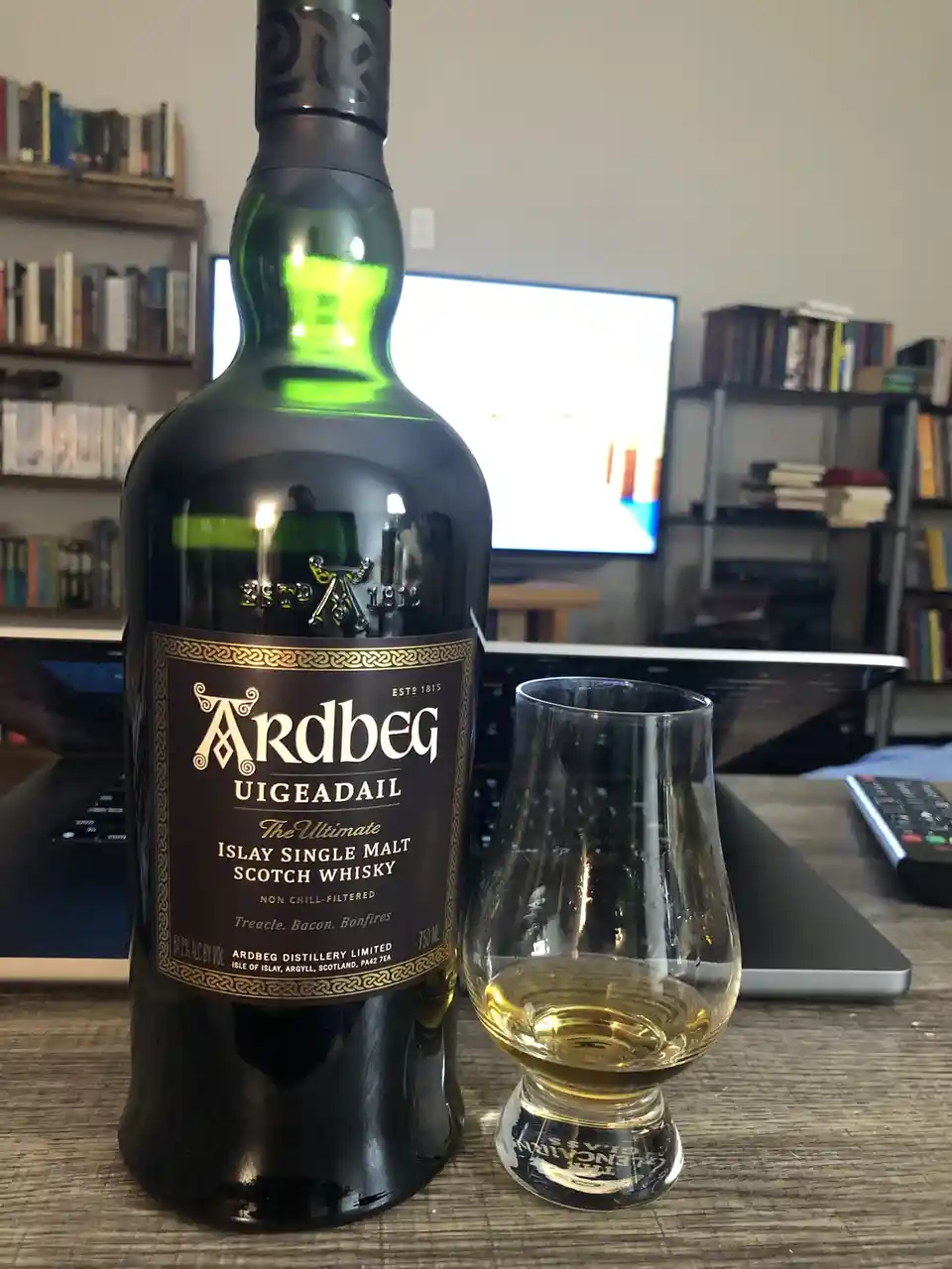 A bottle of Ardbeg Uigeadail Islay Single Malt Scotch Whisky sits next to a tasting glass with a small amount of whisky…