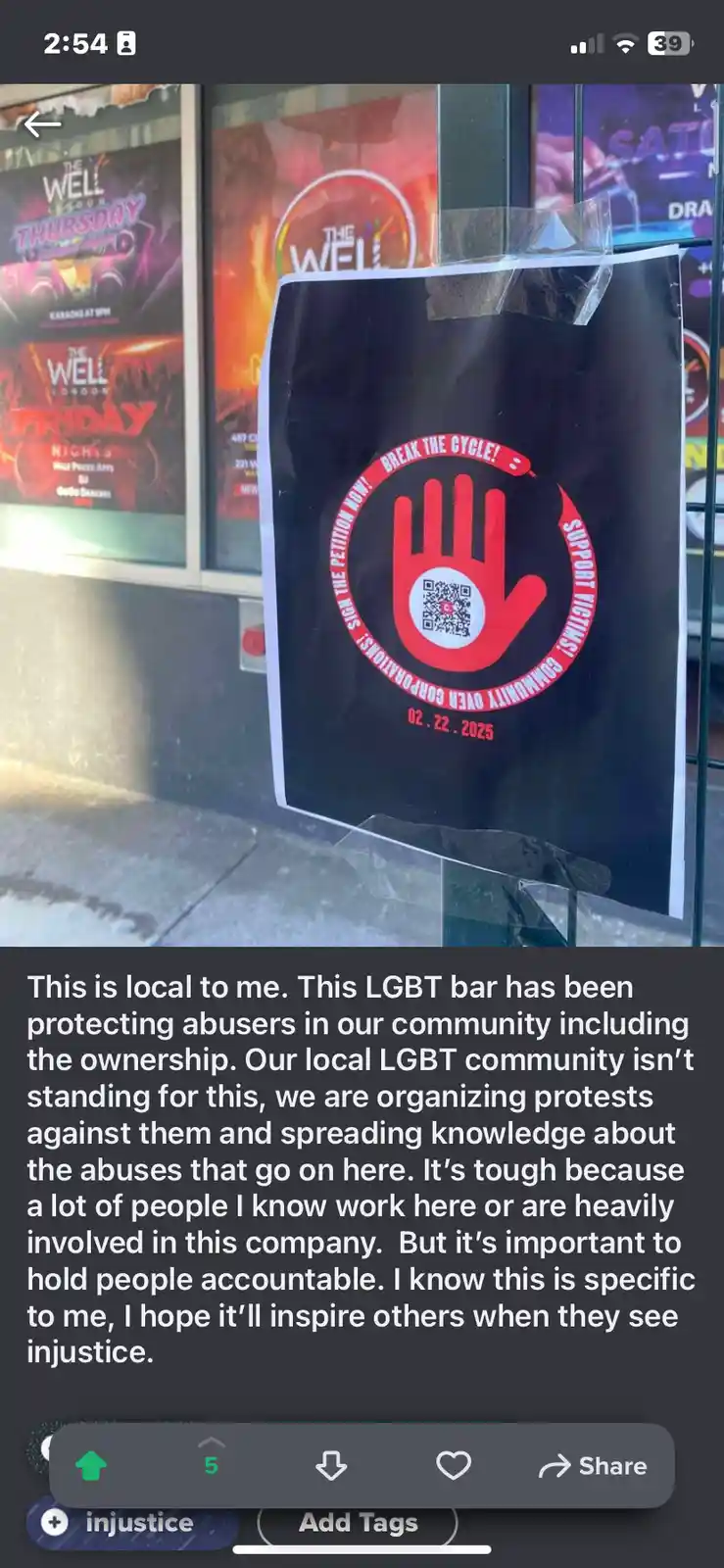 A black poster taped to a glass door features a red handprint logo with a QR code in the center and text reading 'SIGN THE…