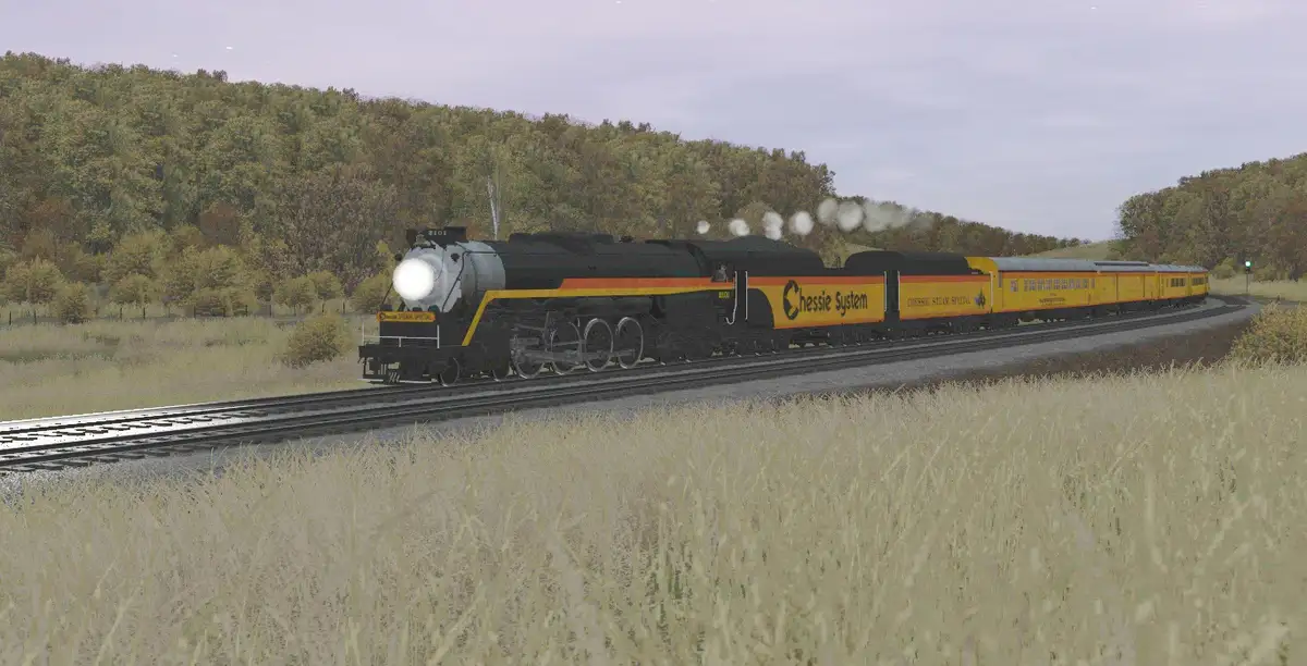 A steam locomotive pulling yellow passenger cars labeled 'Chessie System' and 'Chessie Steak Special' travels through a…