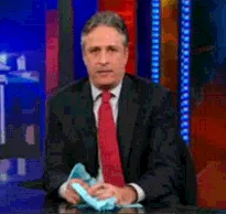 A six-panel image sequence shows a man in a black suit and red tie sitting at a desk, holding a blue cloth. He starts with a…