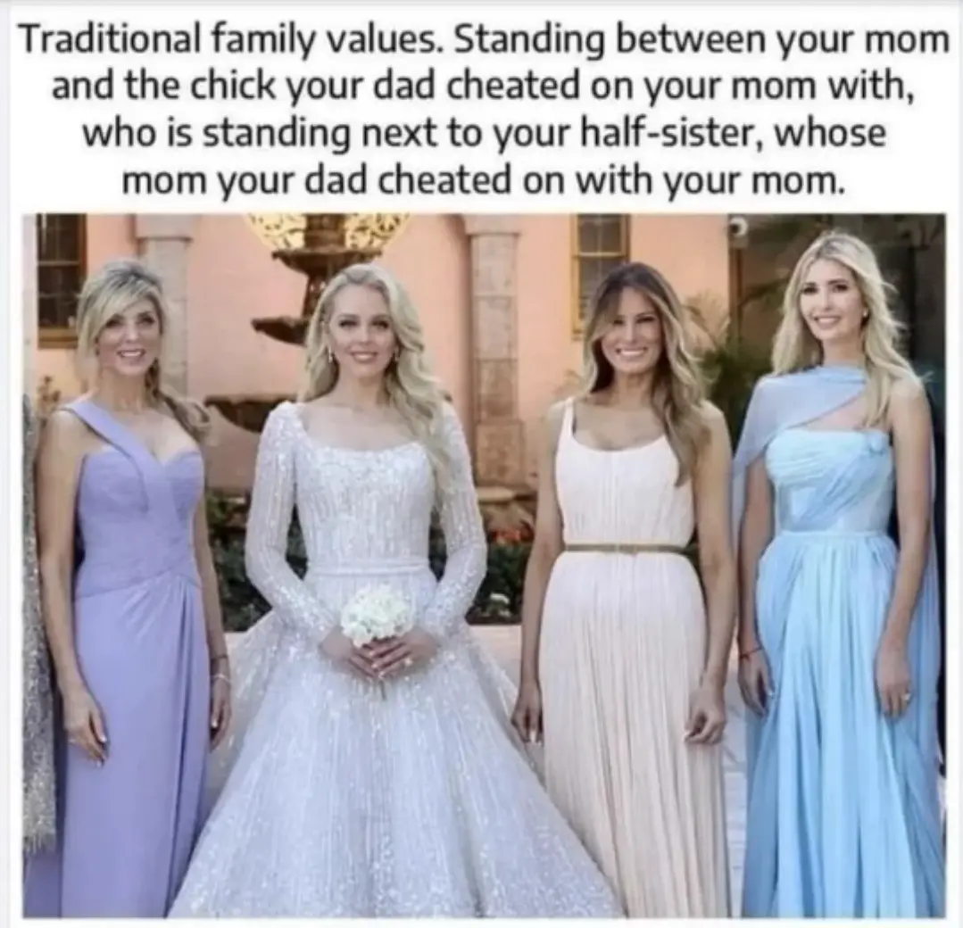 Four women in formal dresses stand together outdoors, smiling. The central woman wears a white wedding gown holding a…
