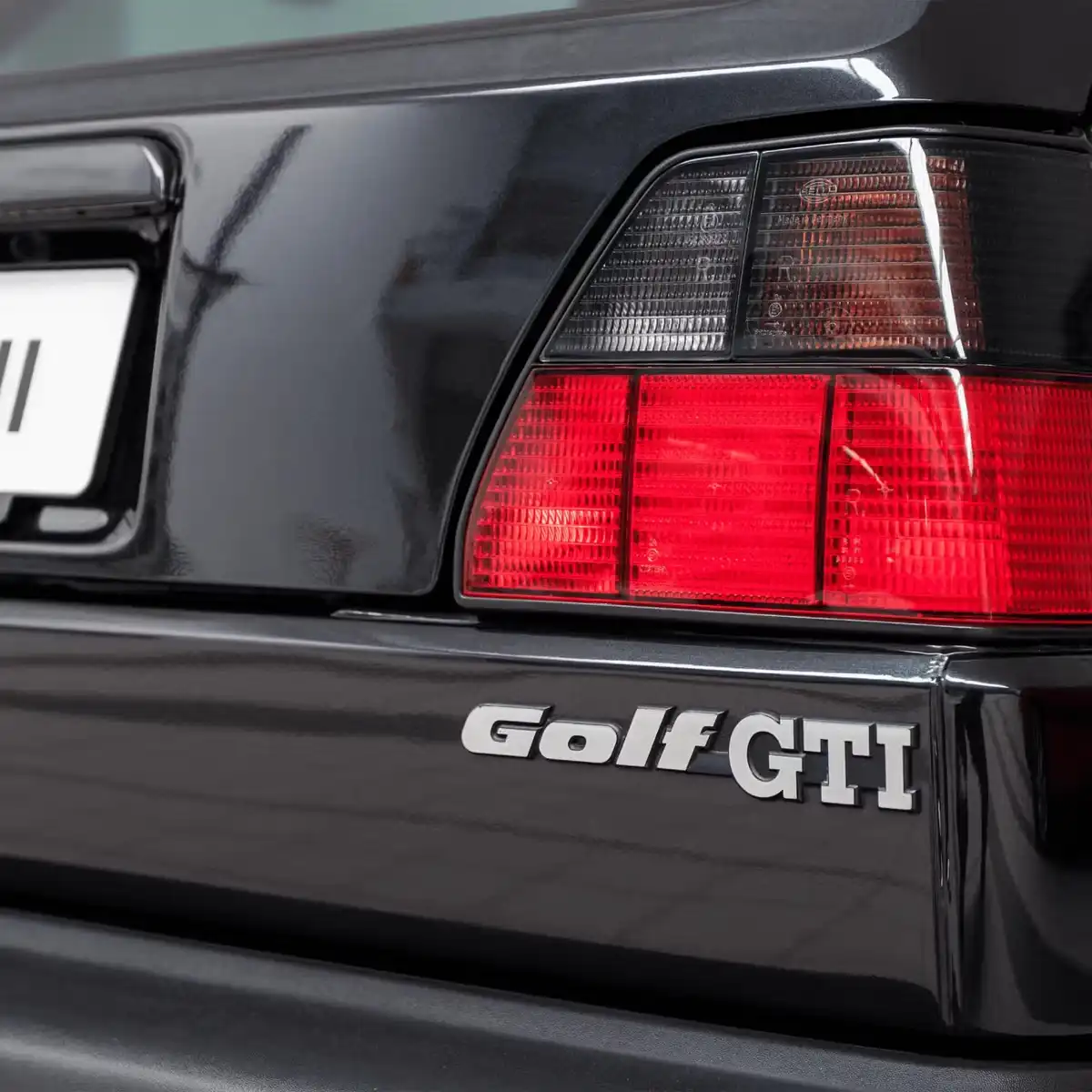 A close-up shot of the rear of a black Volkswagen Golf GTI, showing its distinctive taillights and the 'Golf GTI' badge on…