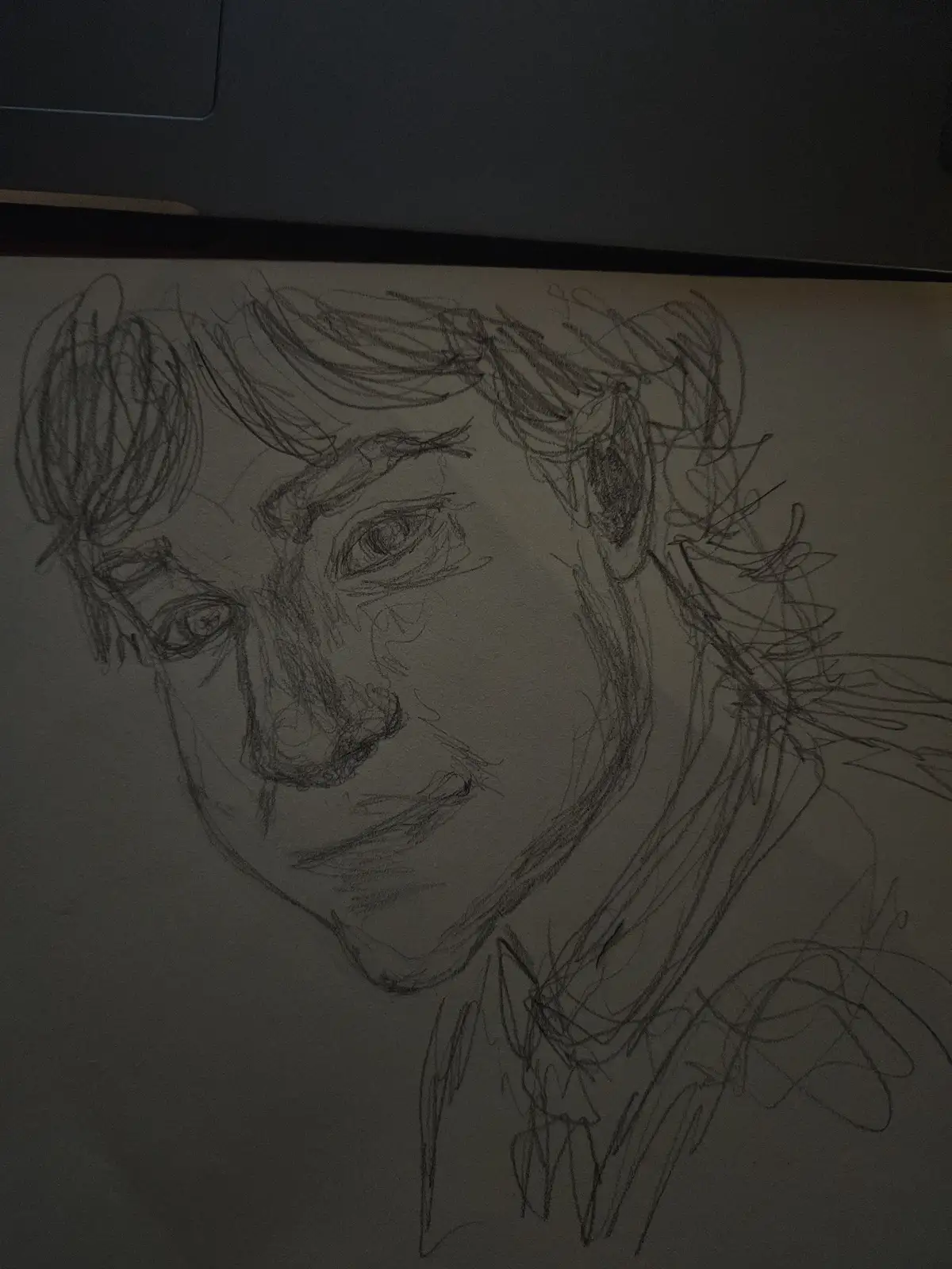 A rough pencil sketch of a person's face and upper shoulders on paper, with messy, expressive lines and a slightly tilted…