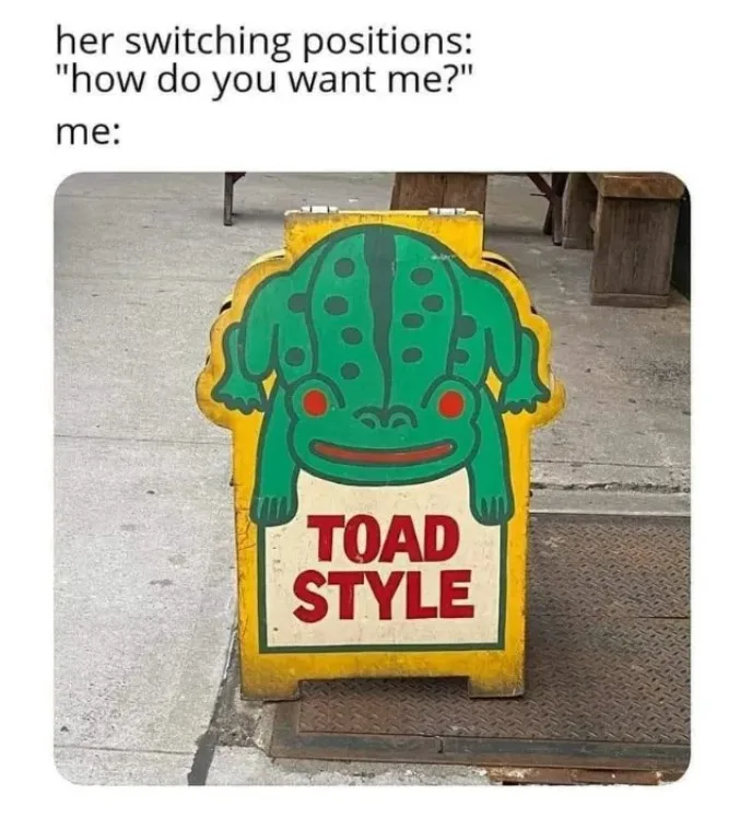 A yellow A-frame sign with a cartoon green toad illustration and the words "TOAD STYLE" in red. The toad is depicted with a…